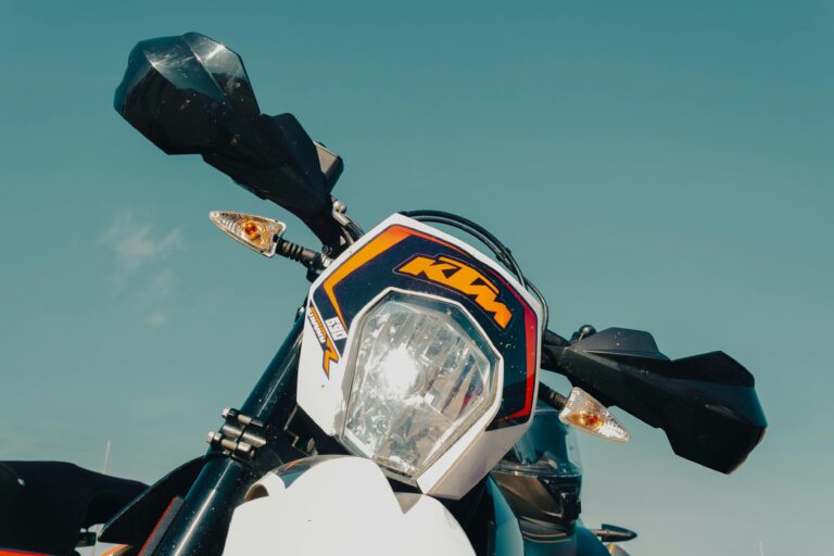 Detailed close-up of a sporty KTM motorcycle headlight in bright daylight showcasing its design.